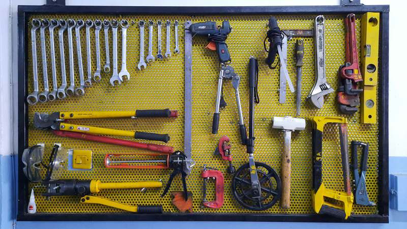 Hand holding heavy-duty vice grips clamped onto steel pipe